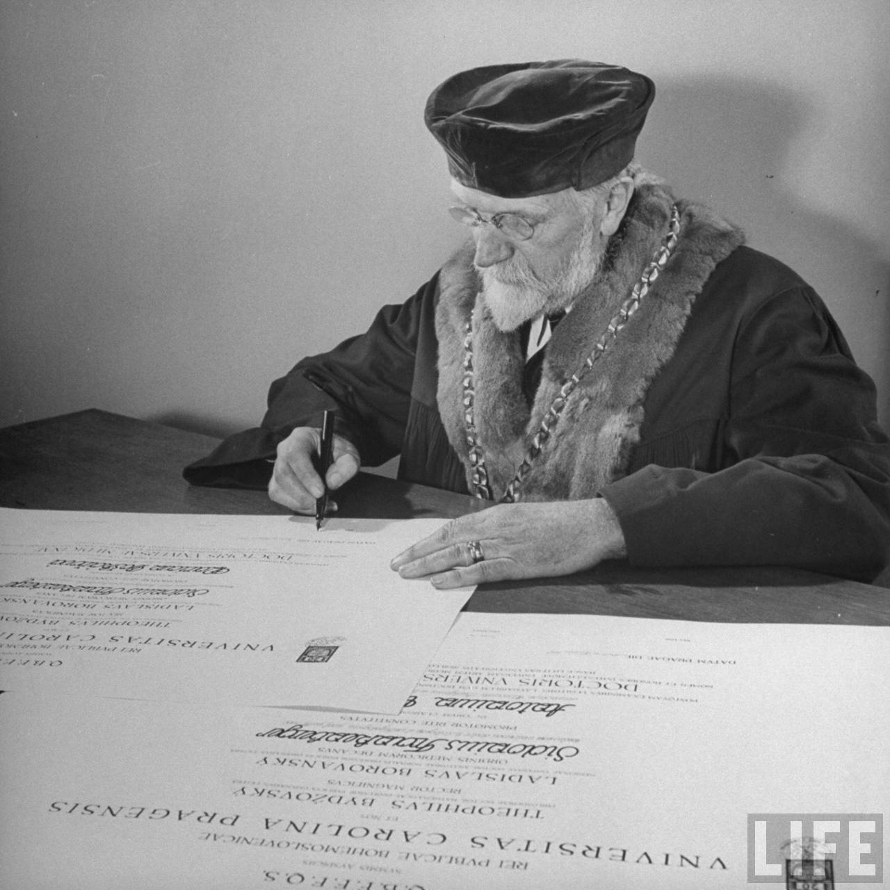 Bohumil Bydzovsky, rector of Charles University, signing diplomas in his office.
